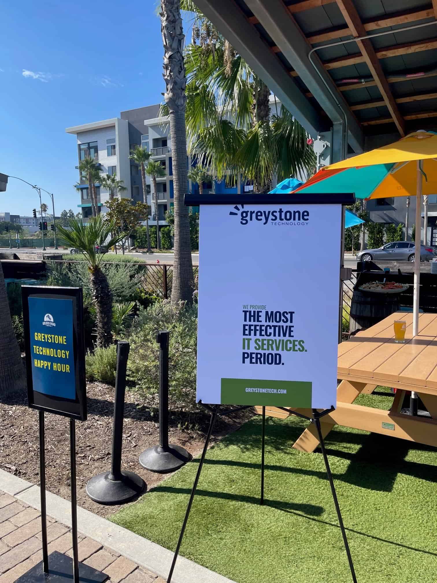 Greystone happy hour and company signs near the event space outdoors.