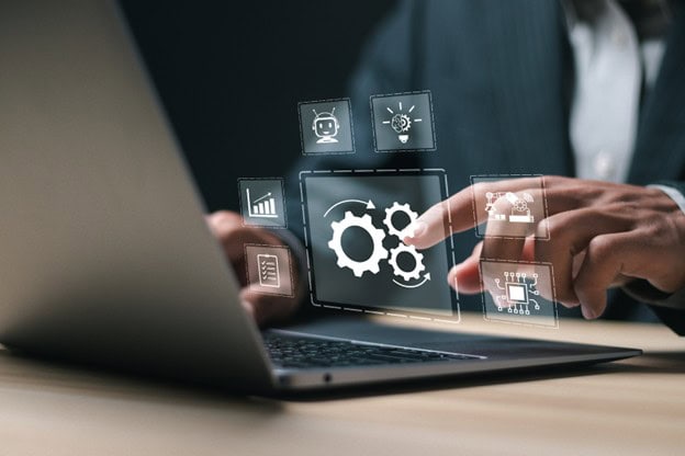 Fingers tapping in midair in front of laptop to show business process automation